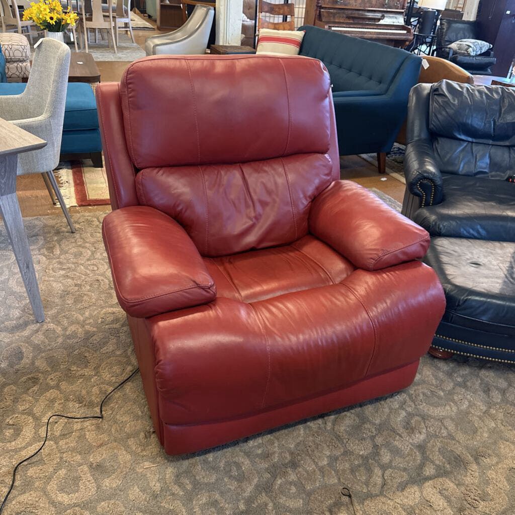 Red leather recliner chair in a showroom setting with other furniture.