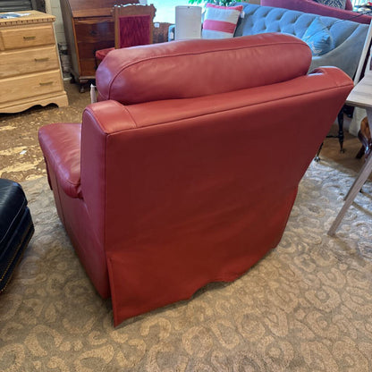 Red leather chair in a room with furniture and decor.