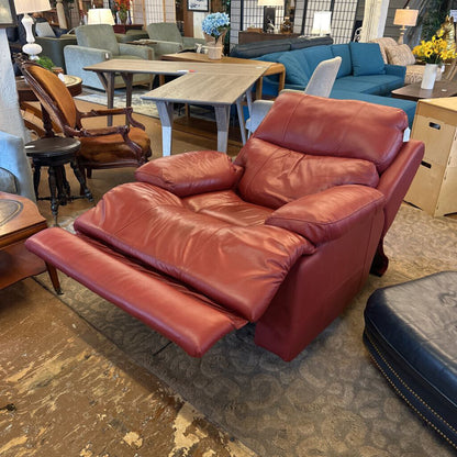 Red leather recliner in a showroom with other furniture.