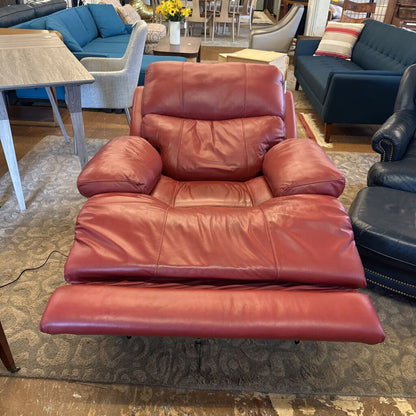 Red leather recliner chair in a furniture store setting with other chairs and tables.