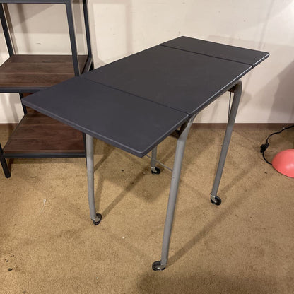 Black folding table on a beige floor with a white wall background