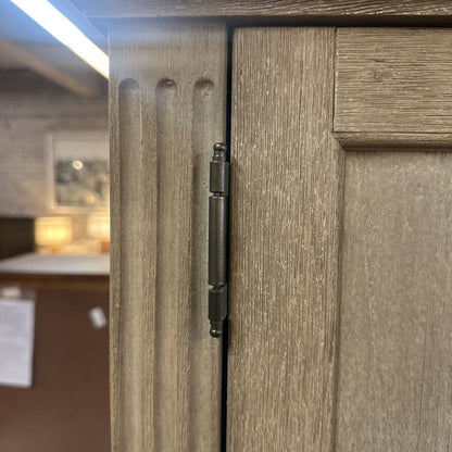 Close-up of a wooden cabinet door with a hinge, blurred background