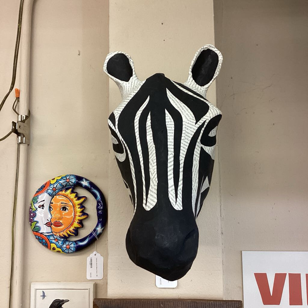 Decorative zebra head wall art on a beige wall with other decorative items.