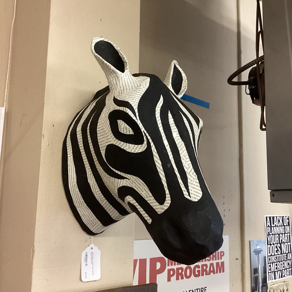 Zebra head sculpture on a wall with promotional posters below