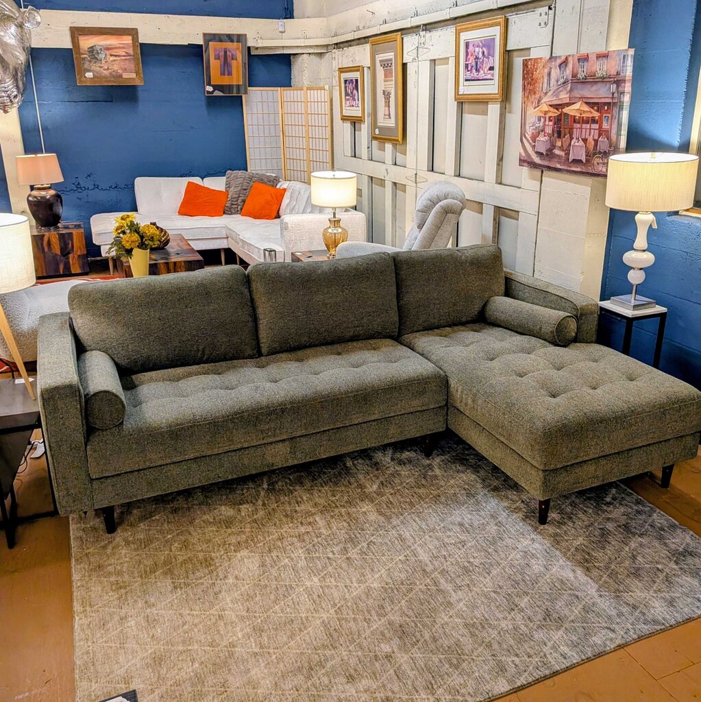 Gray sectional sofa in a showroom with other furniture and decor.