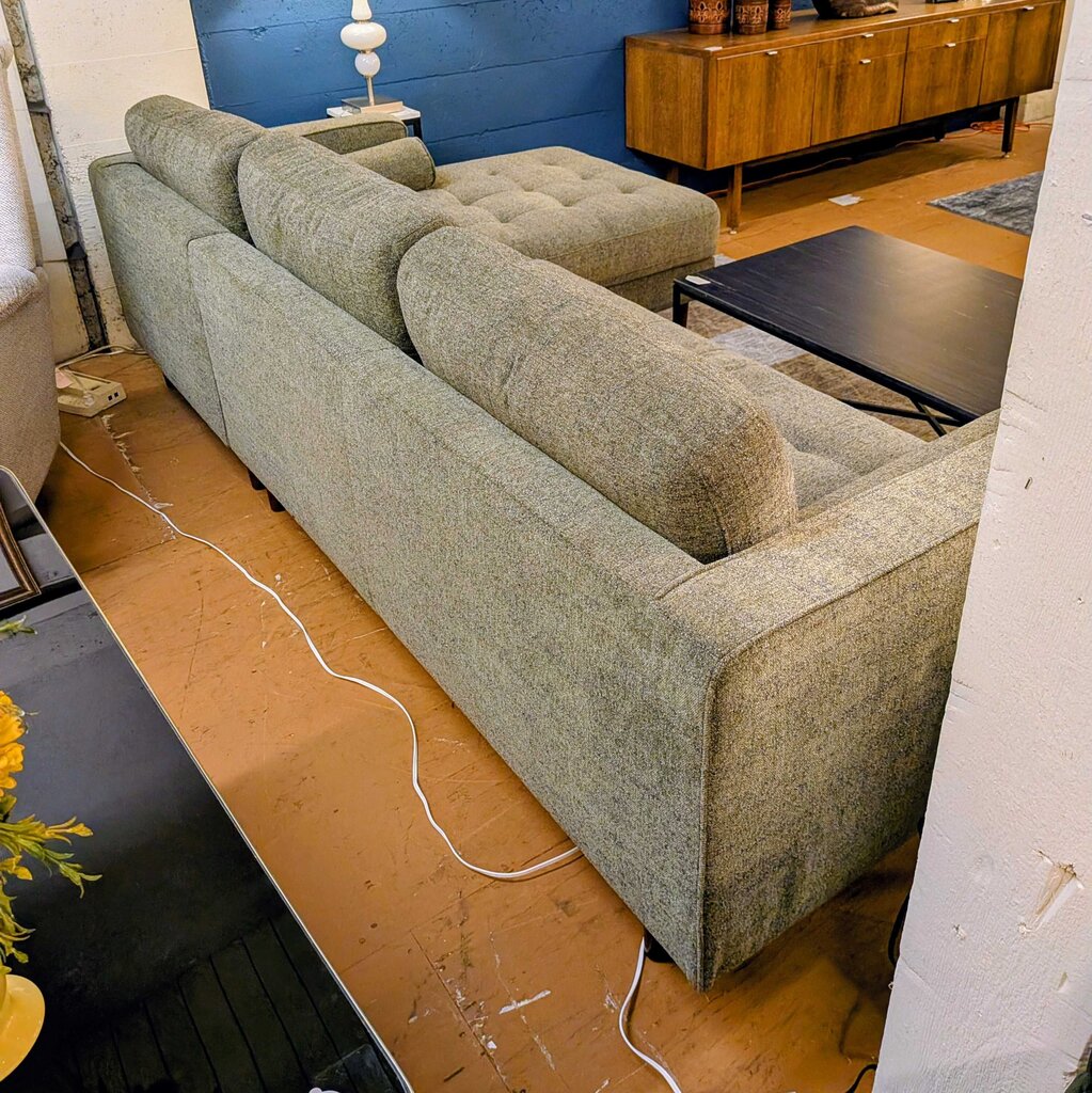 Gray sofa in a room with a wooden floor and furniture.