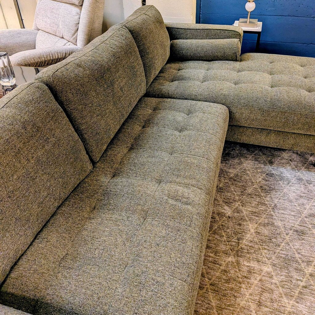 Gray sectional sofa in a room with a rug and chair.