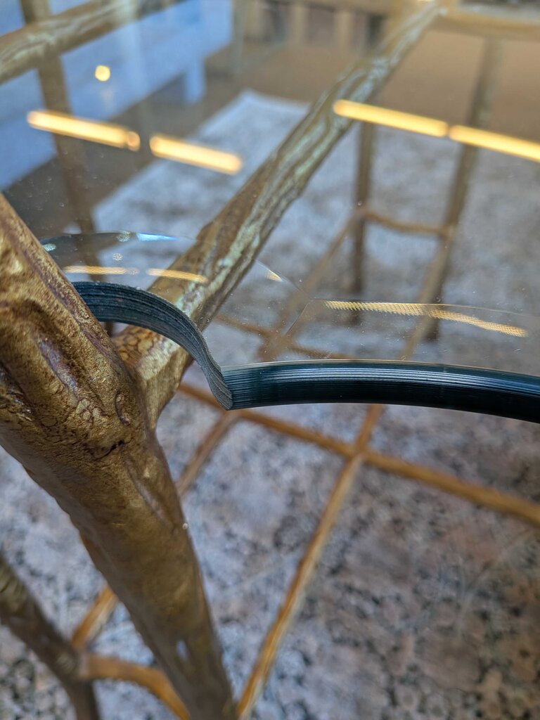 Glass table with gold metal legs on a textured floor