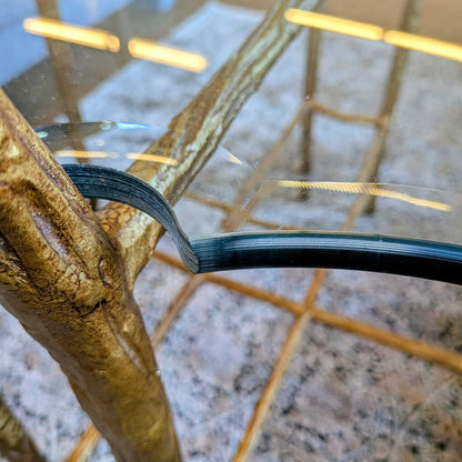 Close-up of a glass table with a gold metal frame on a marble surface.