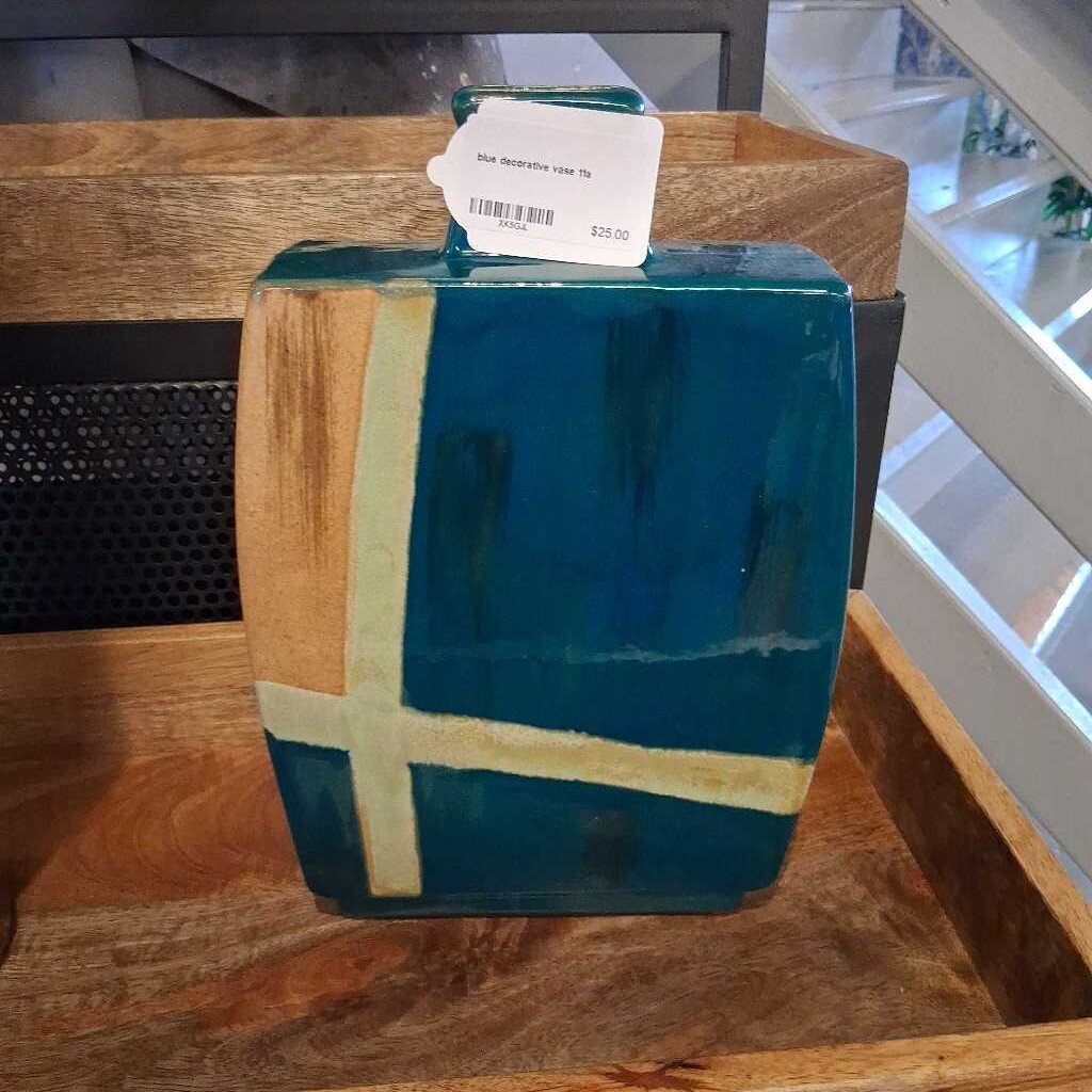 Blue decorative vase with a white label on a wooden surface