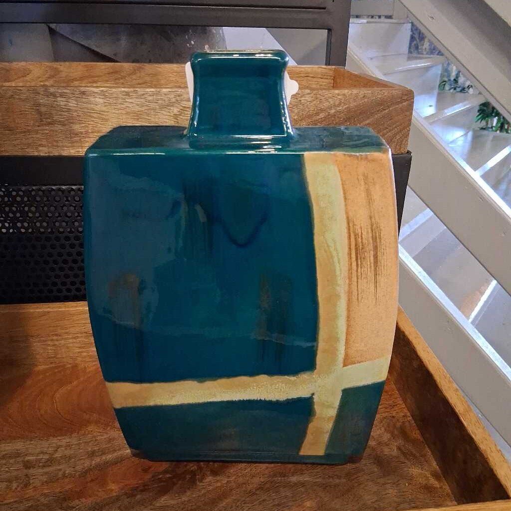 Teal and gold ceramic vase on a wooden surface