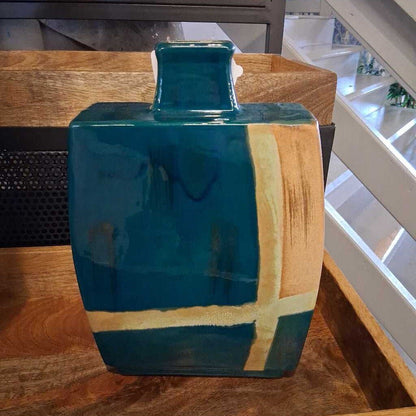 Teal and gold ceramic vase on a wooden surface