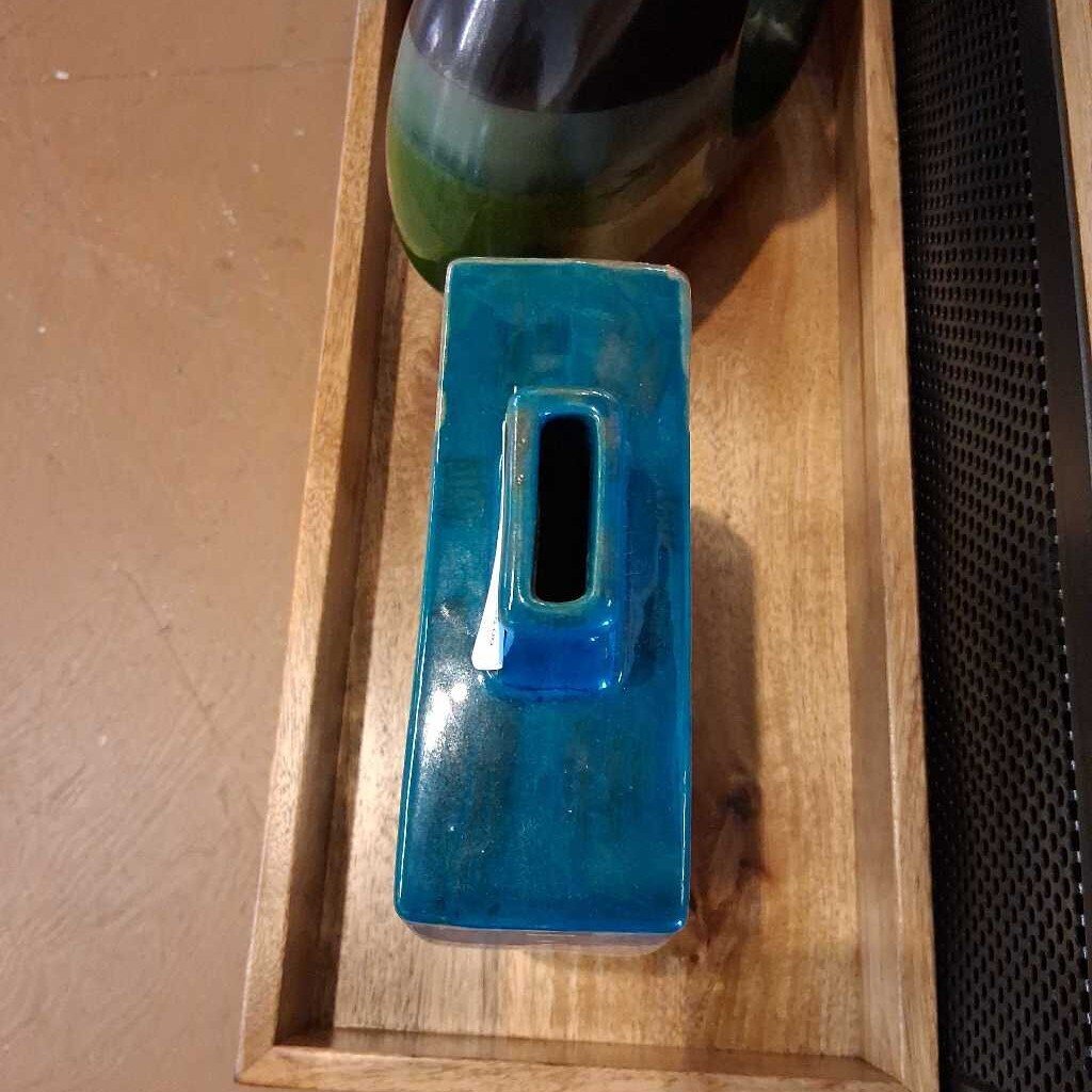 Blue rectangular object on a wooden surface with a black textured object next to it.
