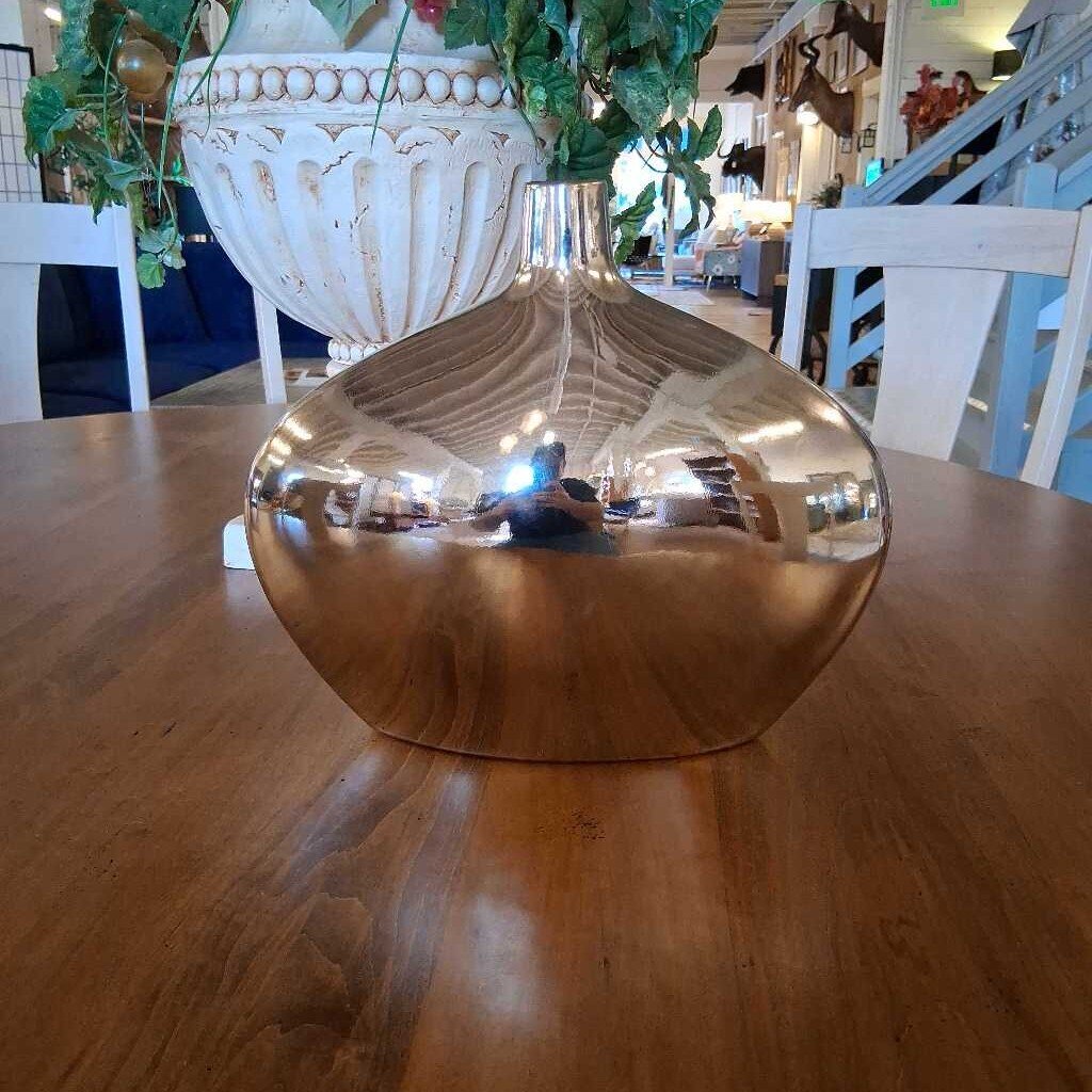 Gold reflective vase on a wooden table with blurred indoor background