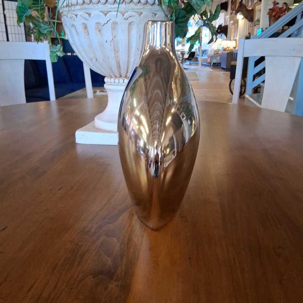 Gold vase on a wooden table with a blurred indoor background
