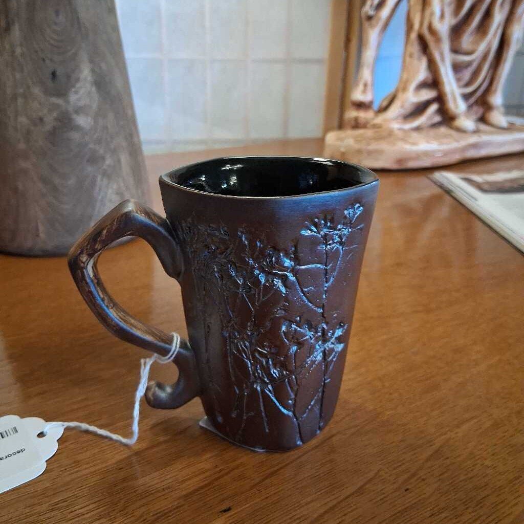 Brown ceramic mug with embossed design on a wooden surface