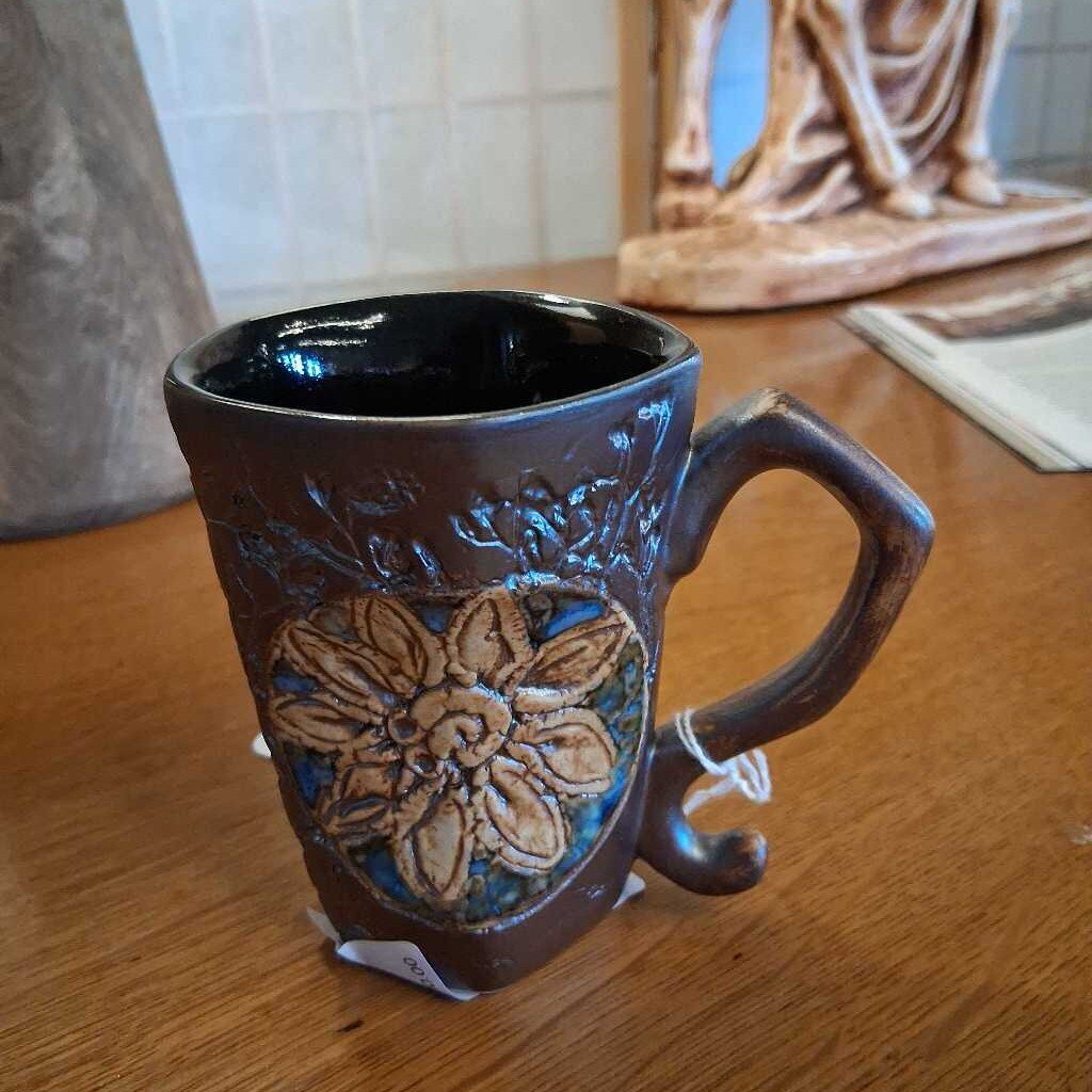 Brown ceramic mug with floral design on a wooden surface