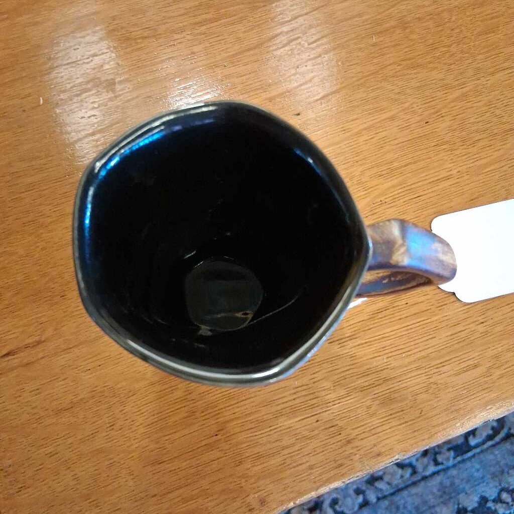 Black mug with a silver handle on a wooden surface