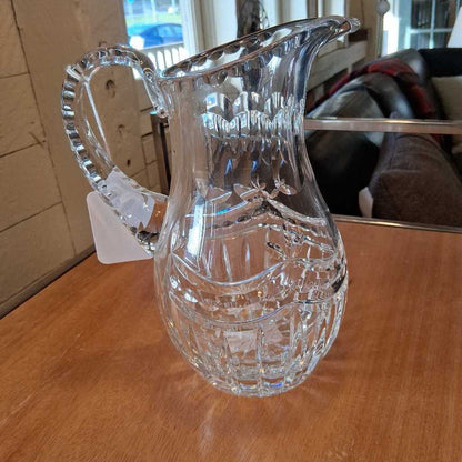 Clear glass pitcher on a wooden surface with a blurred background