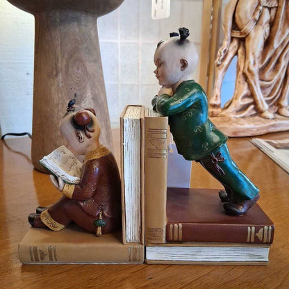 Decorative bookends shaped like traditional figures on a wooden surface.