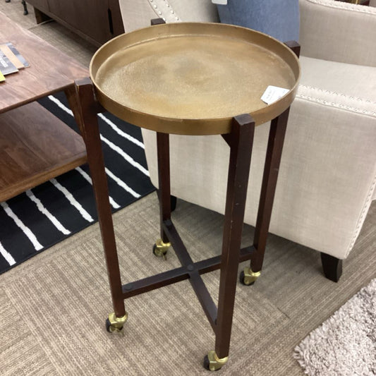 Small round table with a gold tray on top in a room setting.