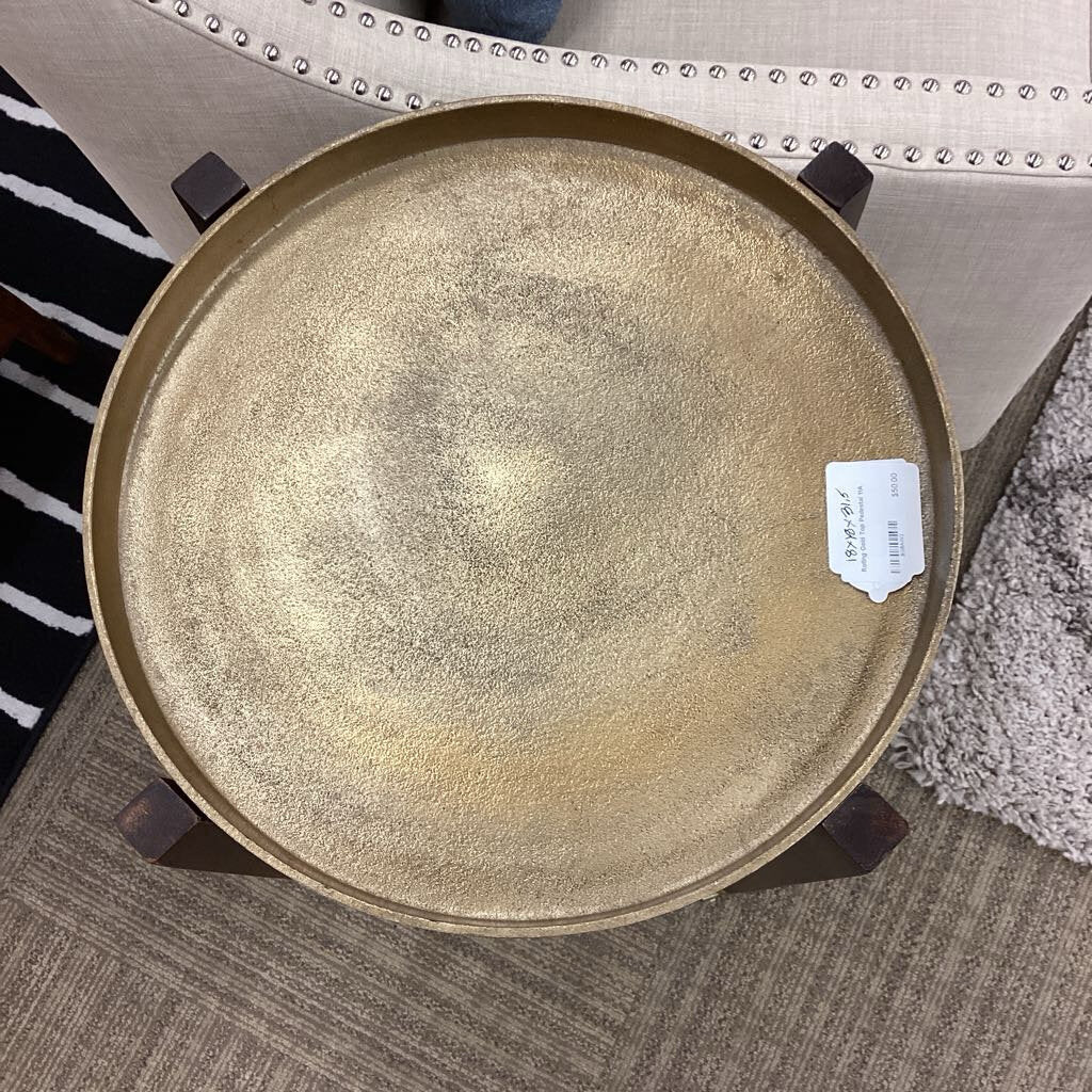 Round metallic tray on a textured surface with a label