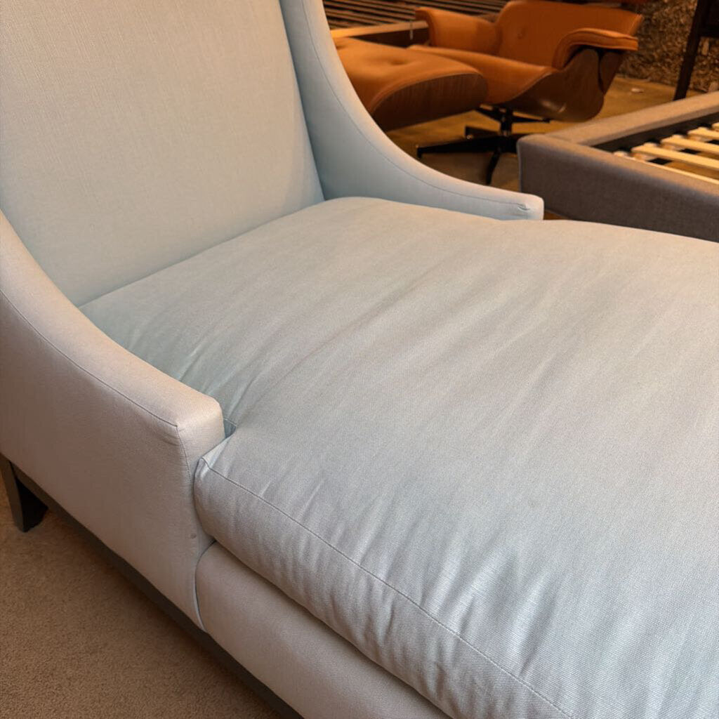 Light gray chaise lounge chair in a room with other furniture.