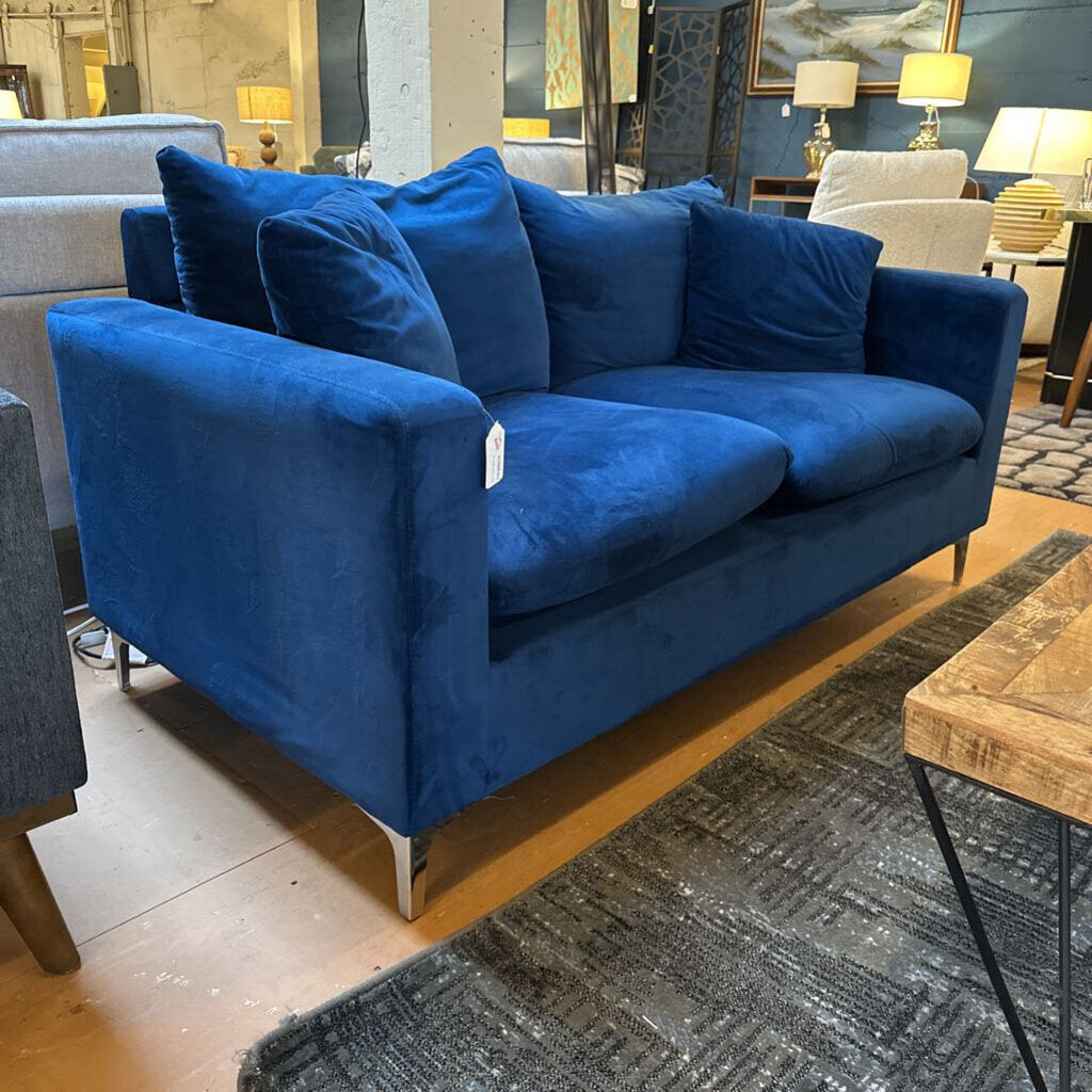 Blue sofa in a showroom setting with other furniture and decor.