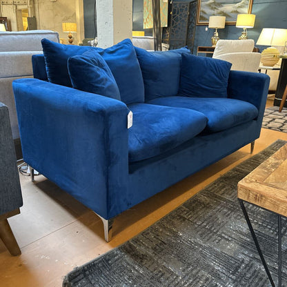 Blue sofa in a showroom setting with other furniture and decor.