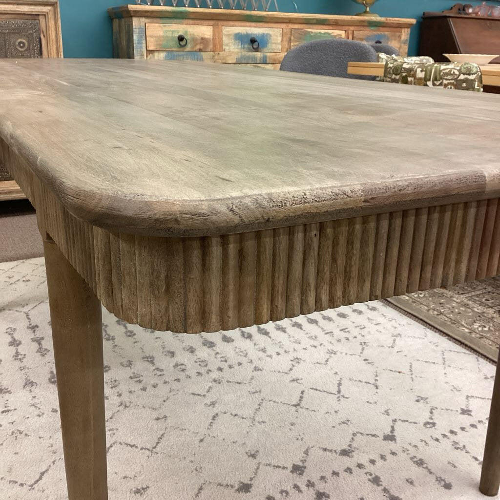 Wooden dining table with a textured surface in a room setting.