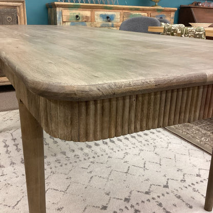 Wooden dining table with a textured surface in a room setting.