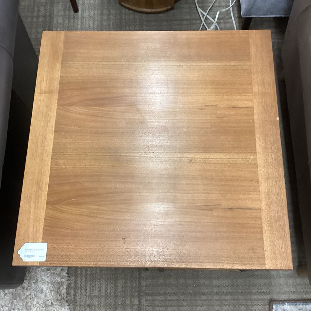 Wooden side table with a visible brand label on a carpeted floor