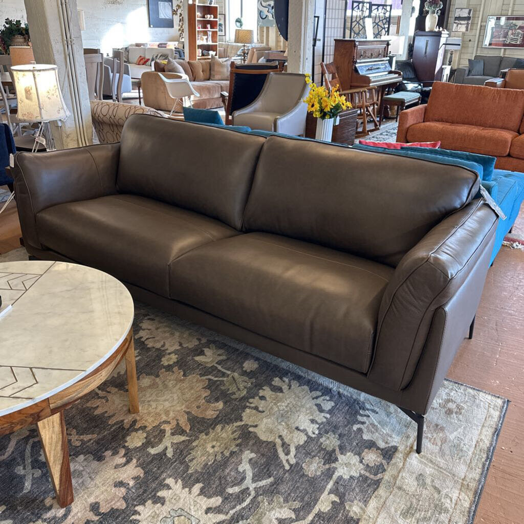 Brown leather sofa in a showroom with other furniture and decor.