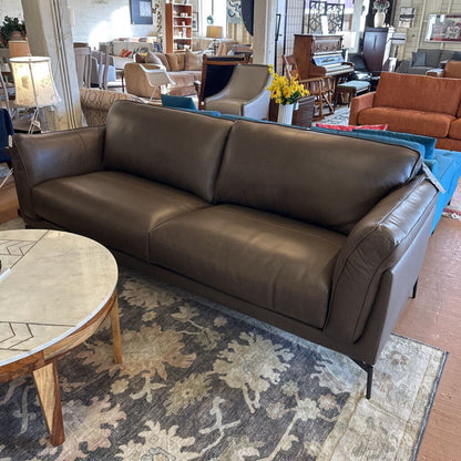 Brown leather sofa in a showroom with other furniture and decor.