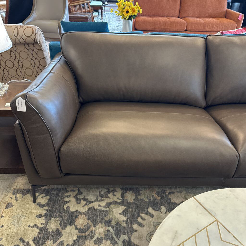 Brown leather sofa in a living room setting with a rug and furniture.