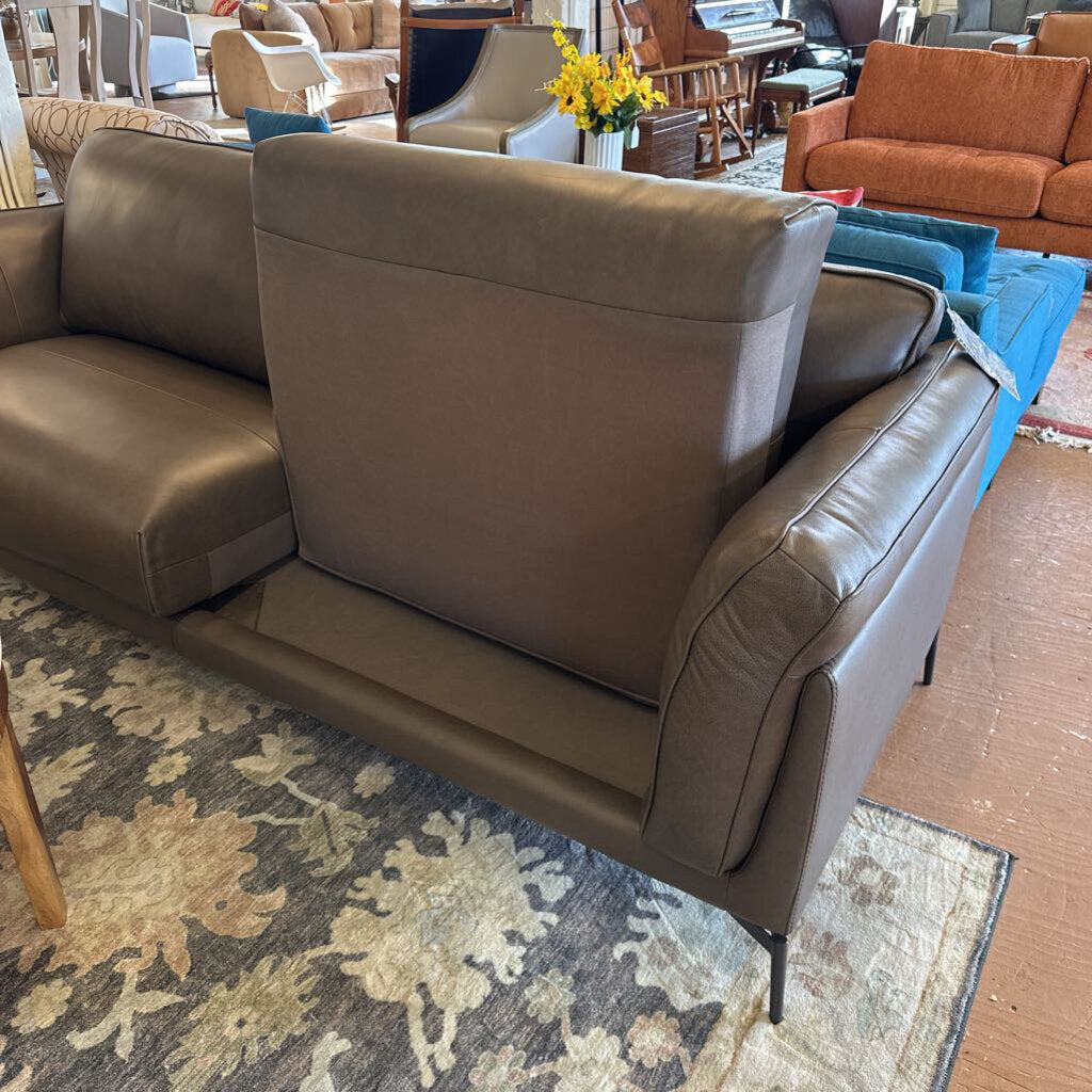 Brown leather sofa in a room with a patterned rug and other furniture.