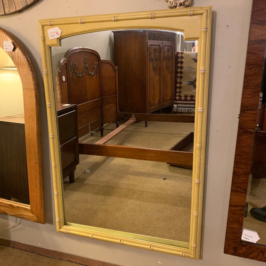 Large mirror with decorative frame reflecting a bedroom setting