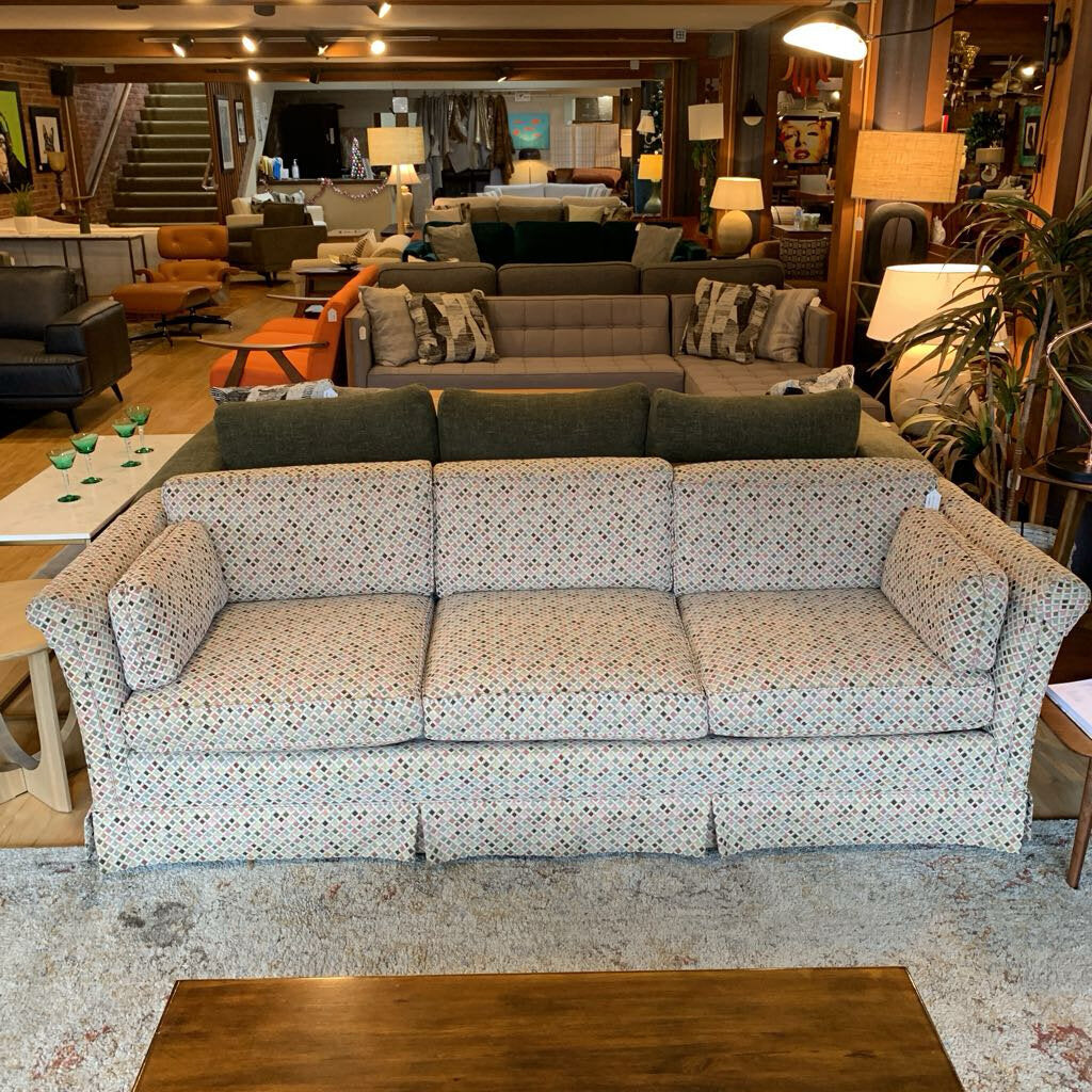 Patterned sofa in a furniture store with various other furniture pieces in the background.