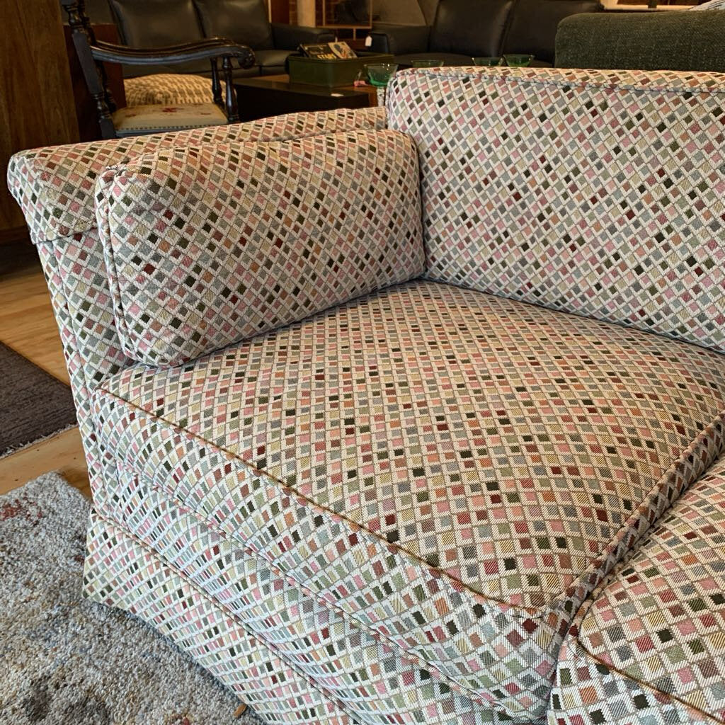 Patterned sofa in a living room setting with wooden floor and furniture.