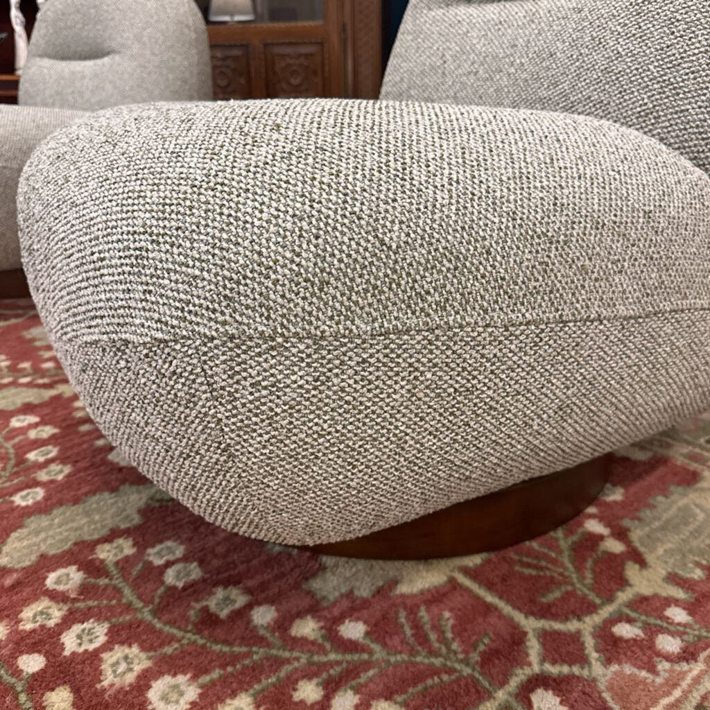 Close-up of a textured gray armchair on a patterned red and beige rug.