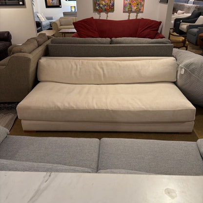 Sectional sofa with beige and gray cushions in a showroom setting.