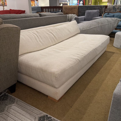 Beige sectional sofa in a showroom setting with other furniture.