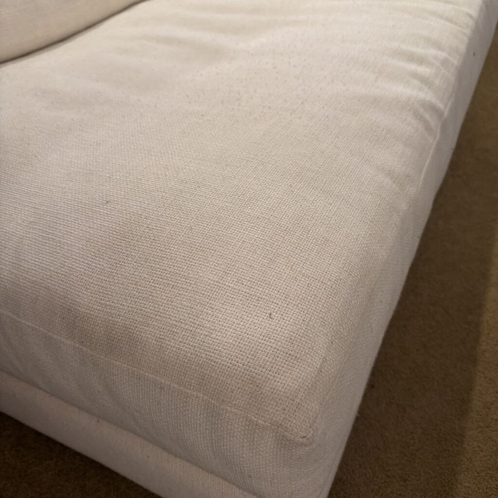 Close-up of a beige fabric surface, possibly a sofa or cushion.