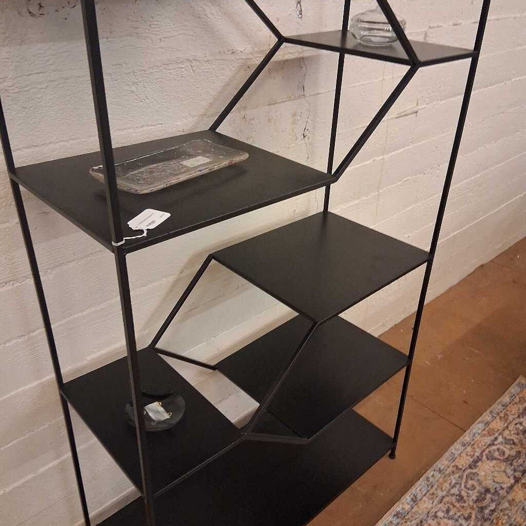 Black metal shelf against a white brick wall