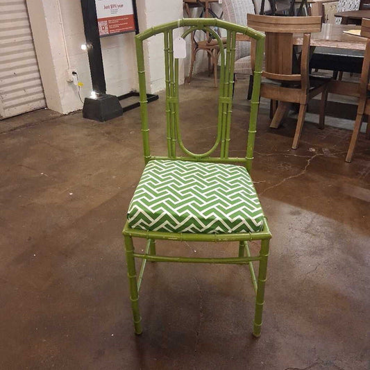 Green metal chair with a patterned cushion on a concrete floor.