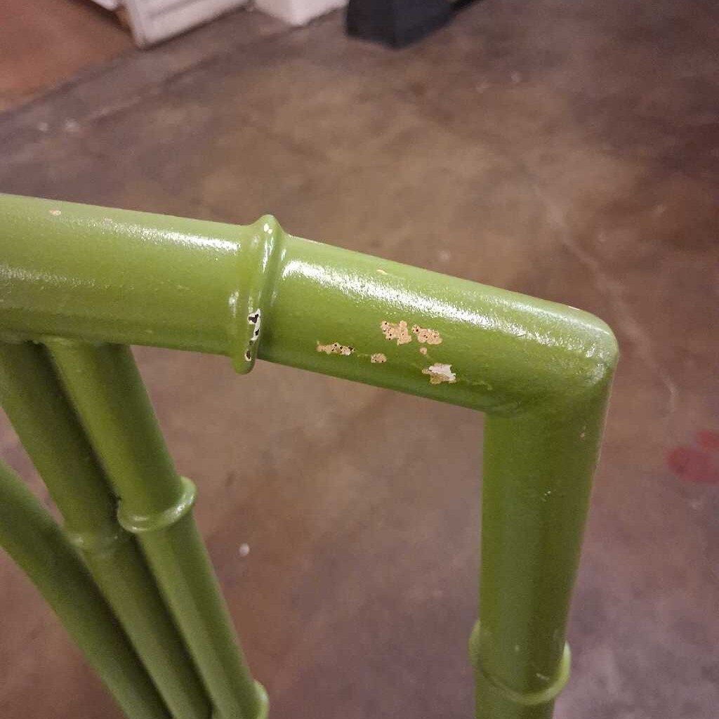Green metal pipe with a slight rust spot on a brown floor