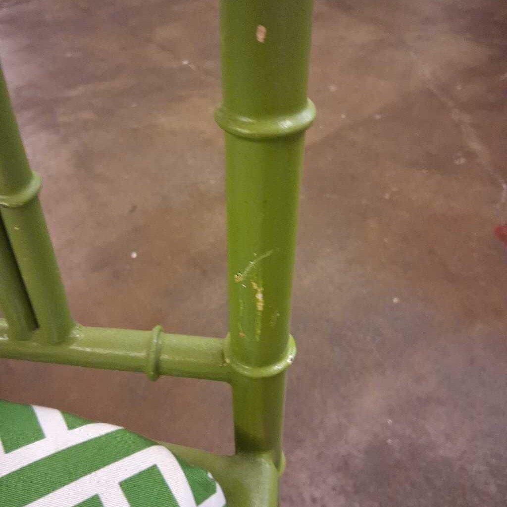 Close-up of a green metal chair frame on a brown floor.