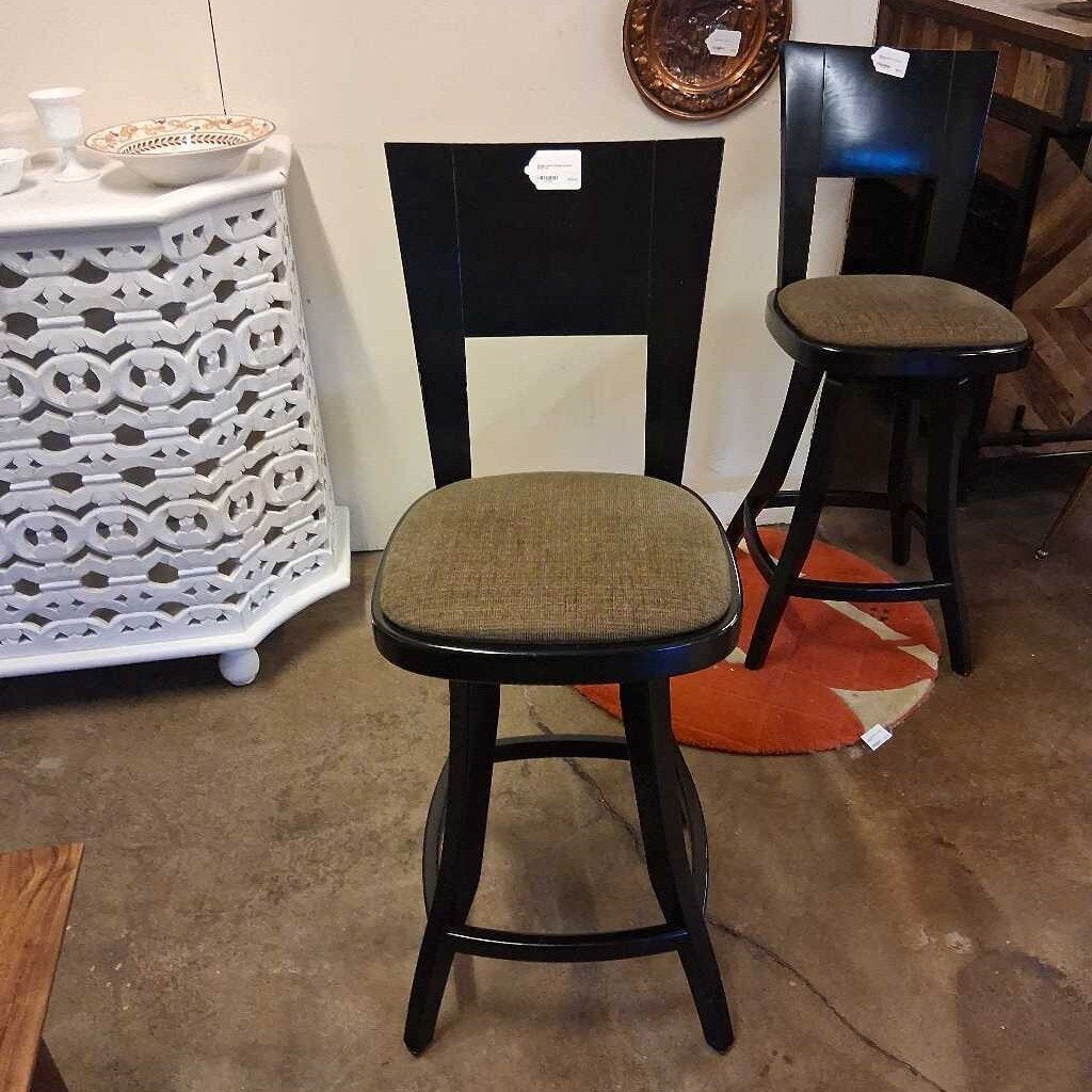 Bar stools with black frames and brown seats in a store setting.