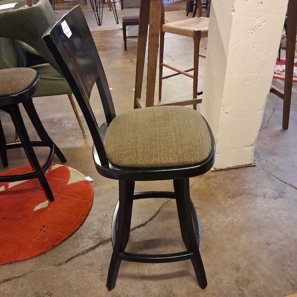 Bar stool with green cushioned seat in a casual setting