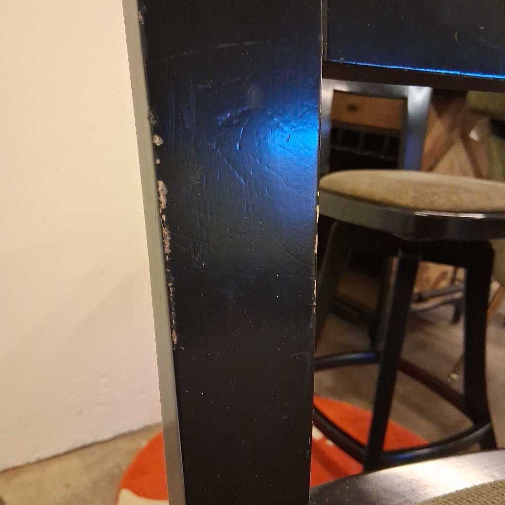 Close-up of a dark blue surface with a chair and stool in the background